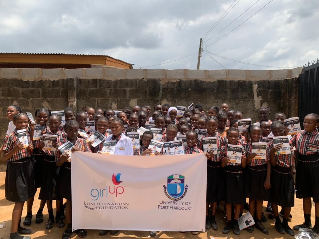Group of students with STEM IN YOU flyers and Girl Up / UNF banner