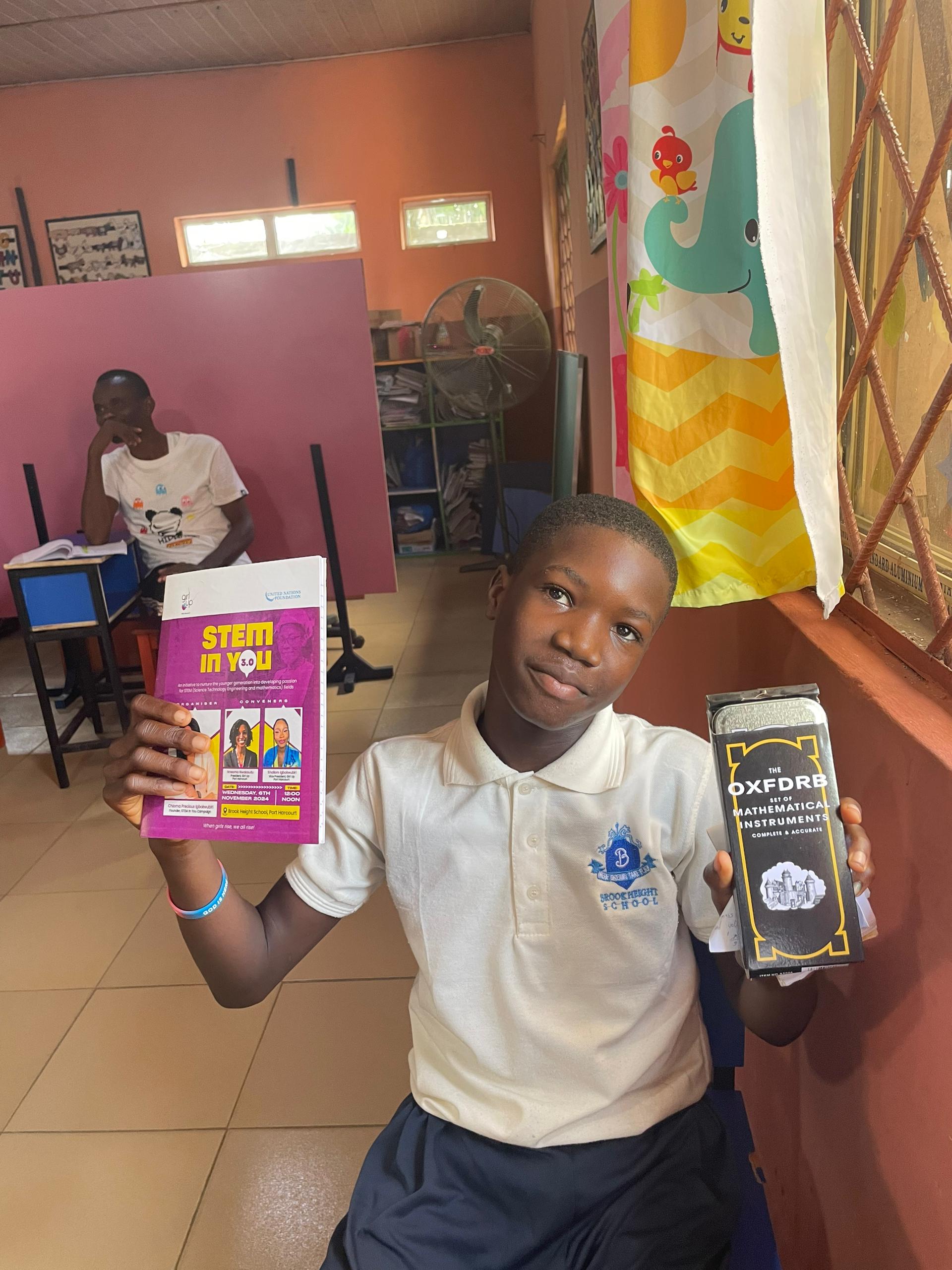 Student holding STEM IN YOU 3.0 flyer and mathematical instruments